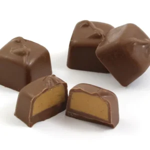 Chocolate squares with a cut piece showing peanut butter filling, beside whipped peanut butter
