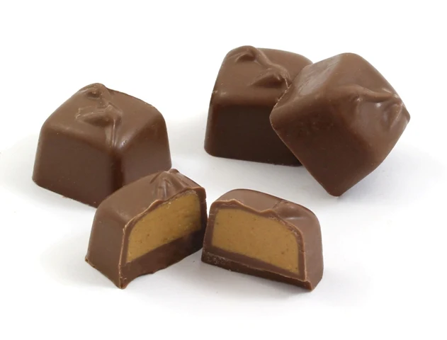 Chocolate squares with a cut piece showing peanut butter filling, beside whipped peanut butter